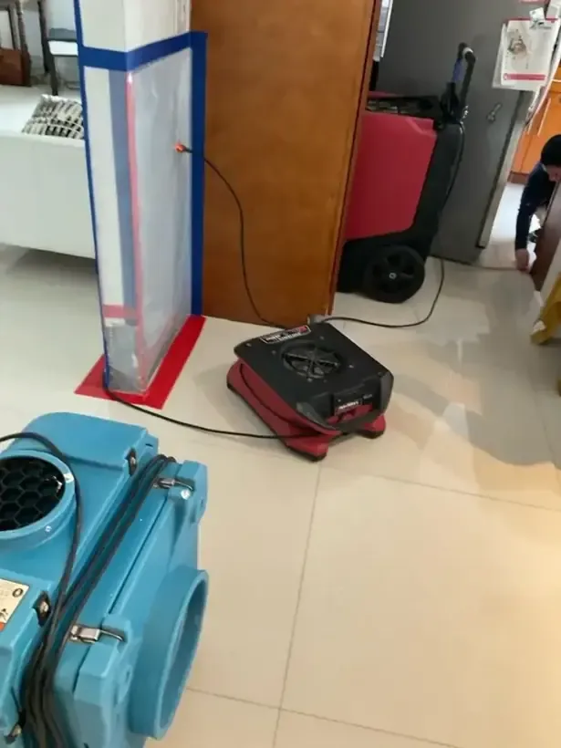 Containment door, air scrubber and dehumidifier set up inside a house during drying