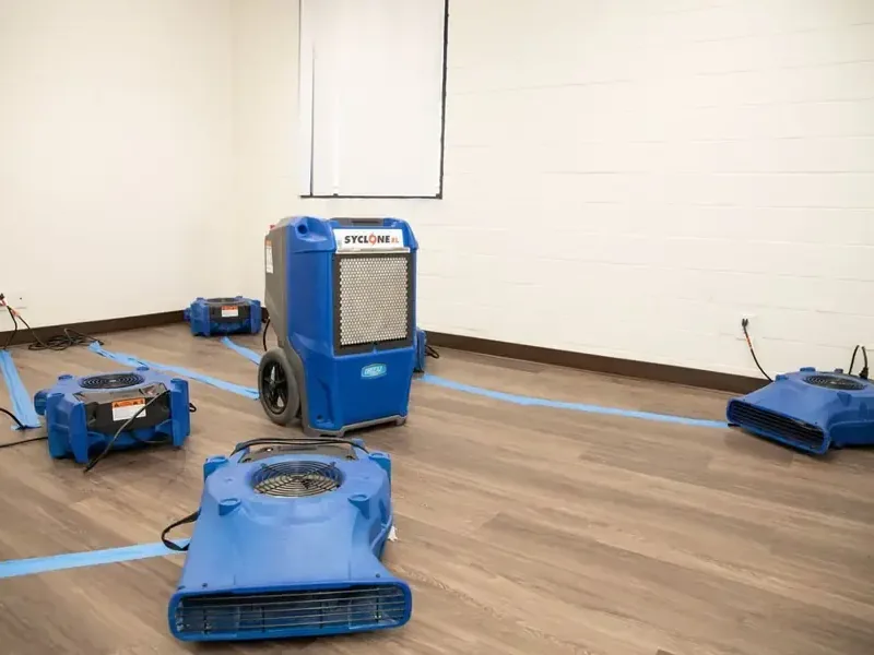 An LGR dehumidifier and a row of low-profile air movers drying out an emptied room