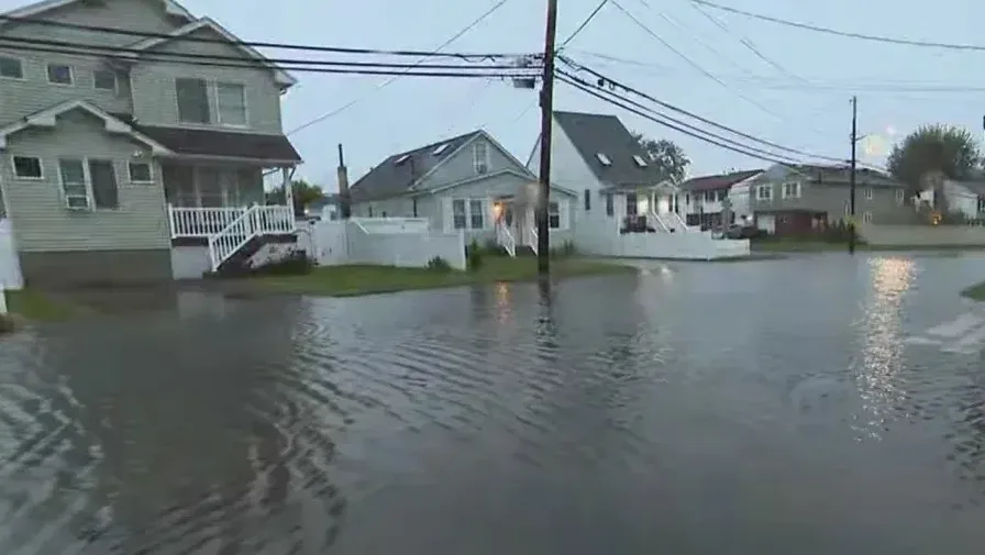 Floodwater spread across a residential street and front yards after a coastal storm