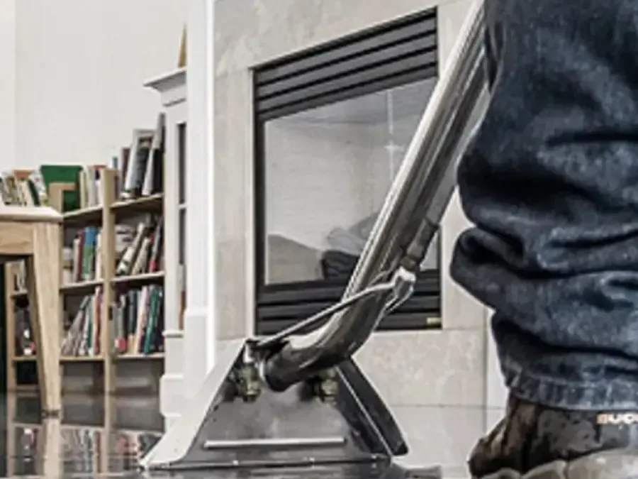 An extraction wand drawing a sheet of standing water off a living room floor